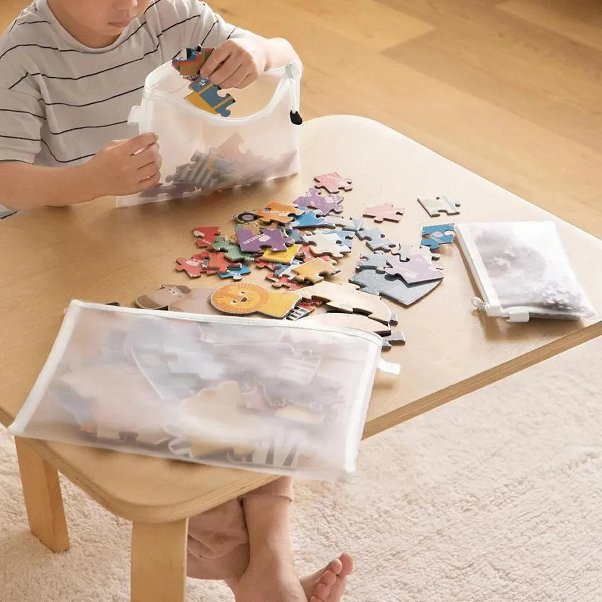 Child playing with puzzle pieces on a wooden table, using clear bags to sort them.