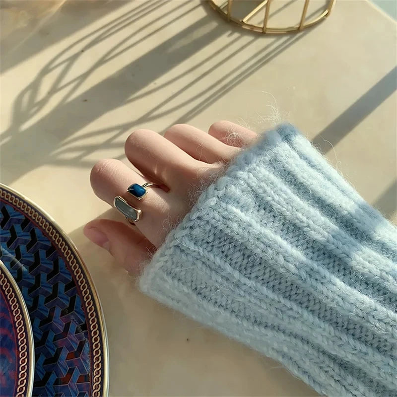 Hand wearing a ring with a blue stone on a textured surface