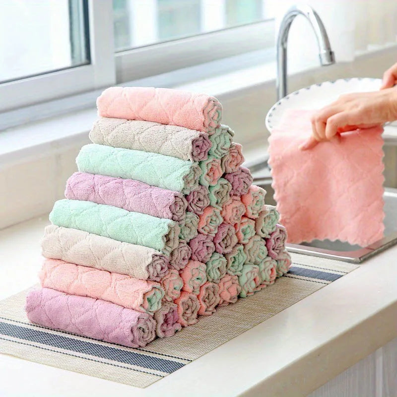 Stack of colorful folded towels on a kitchen counter with a person using a pink towel.