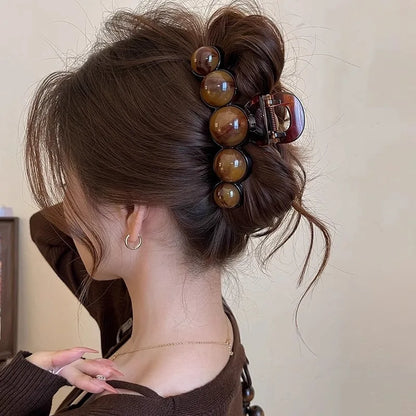 Woman with a stylish hair bun using a decorative hair clip against a neutral background