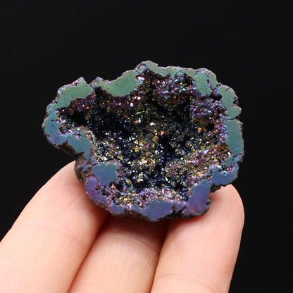 Geode crystal held in a hand against a black background