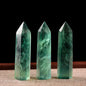 Three green crystal points on a textured surface with a dark background