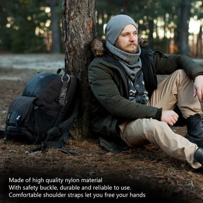 Man sitting against a tree with a backpack, wearing winter clothing.