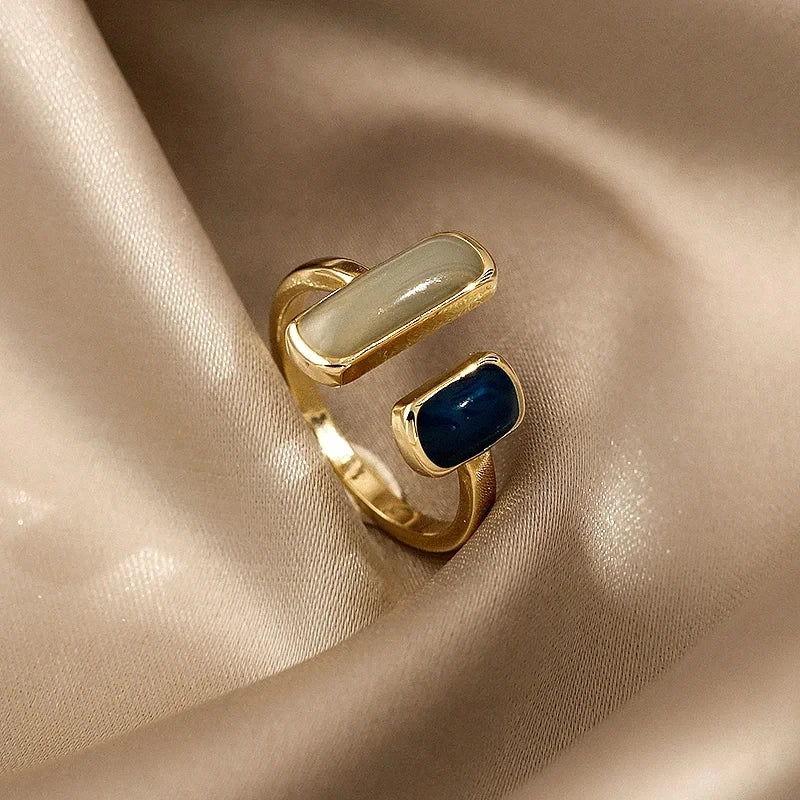 Gold ring with blue and beige stones on a beige fabric background