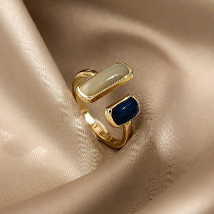 Gold ring with blue and beige stones on a beige fabric background