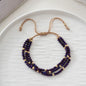 Necklace with purple beads and gold accents on a white plate