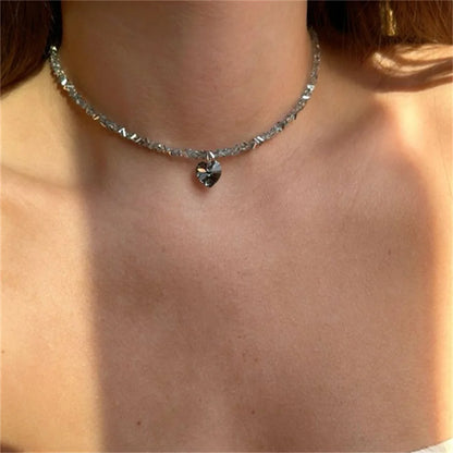 Close-up of a silver necklace with a pendant on a person's neck