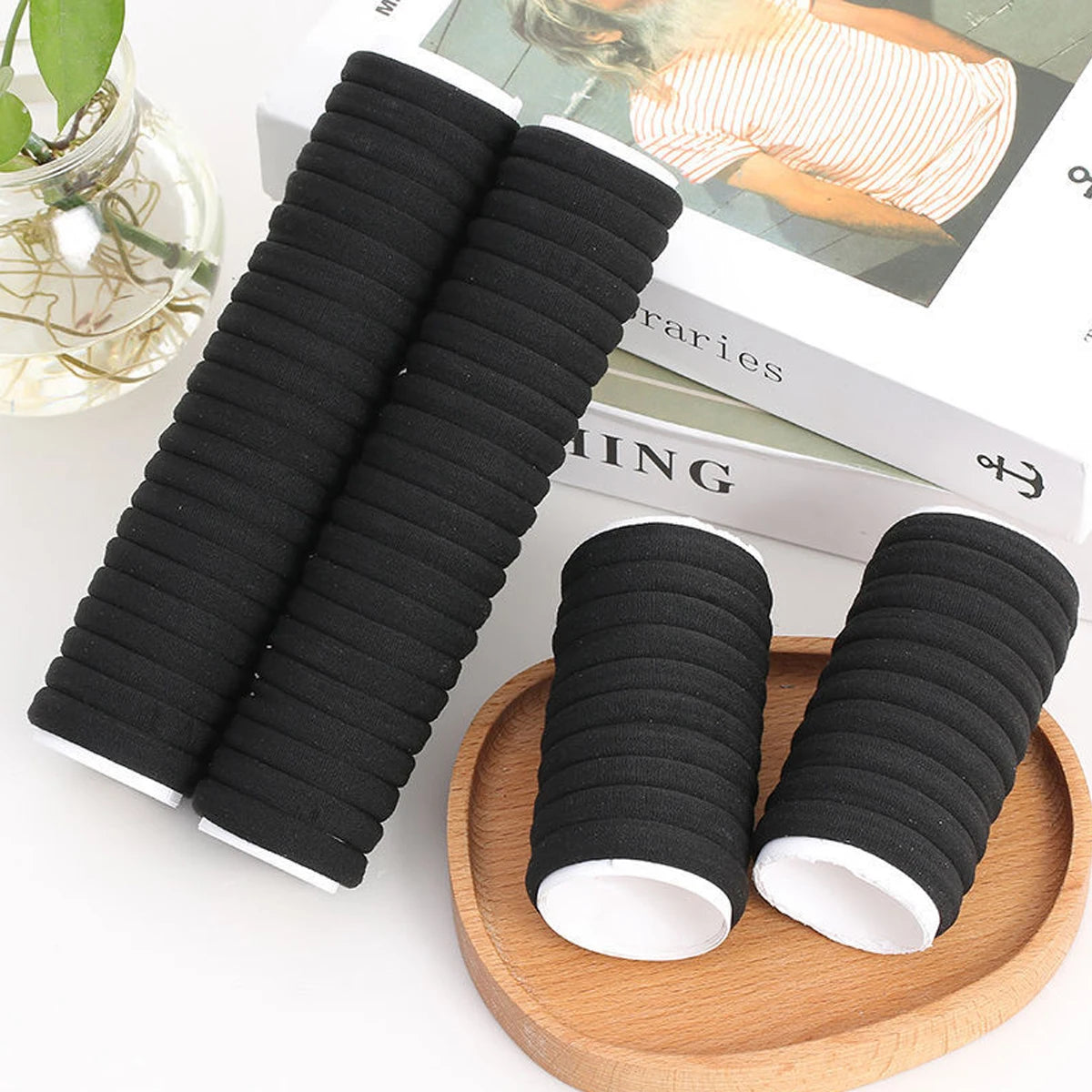 Black hair ties on a wooden plate with a magazine in the background