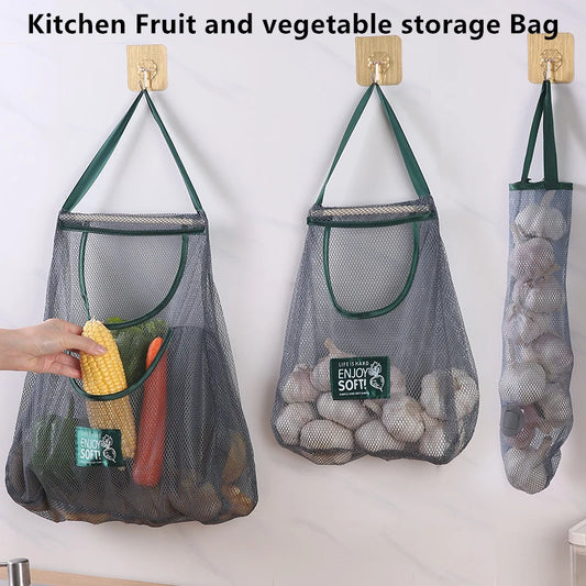 Mesh storage bags for kitchen fruits and vegetables with a hand holding corn, on a white background.