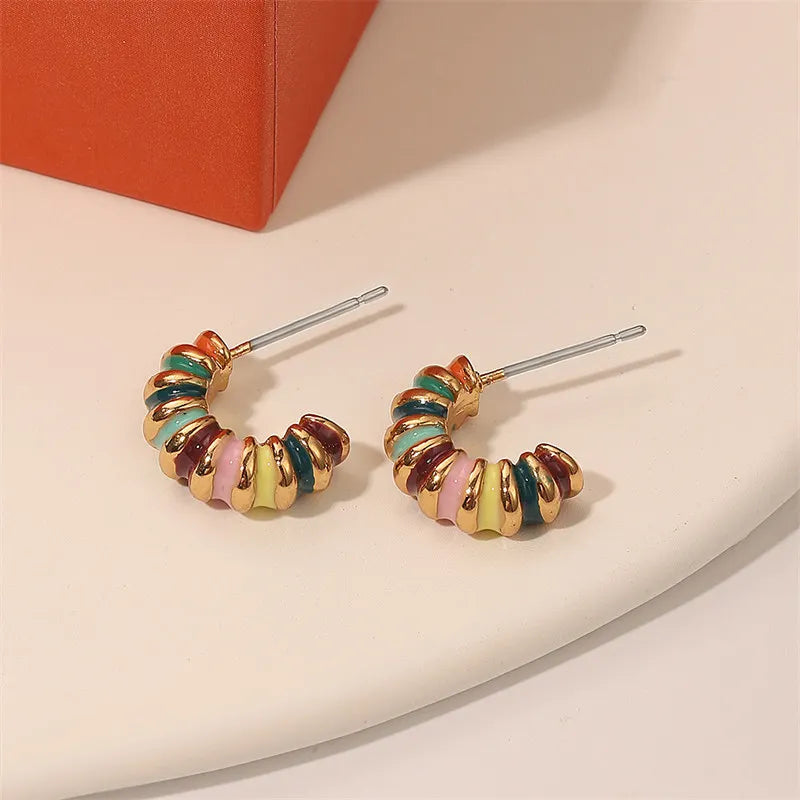 Colorful hoop earrings on a beige surface with an orange box in the background