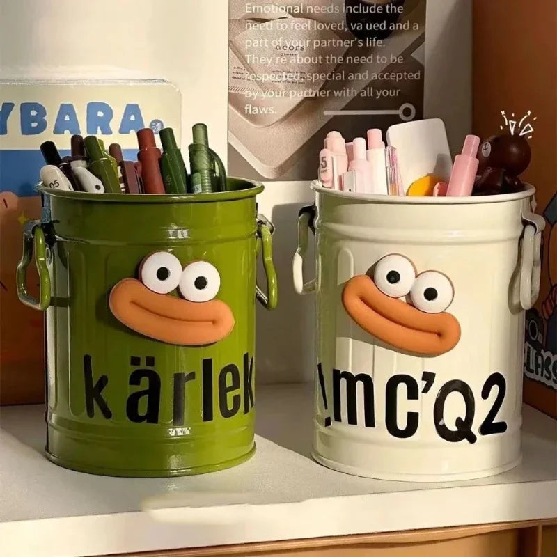 Two colorful buckets with cartoon faces and text, one green and one white, on a shelf.
