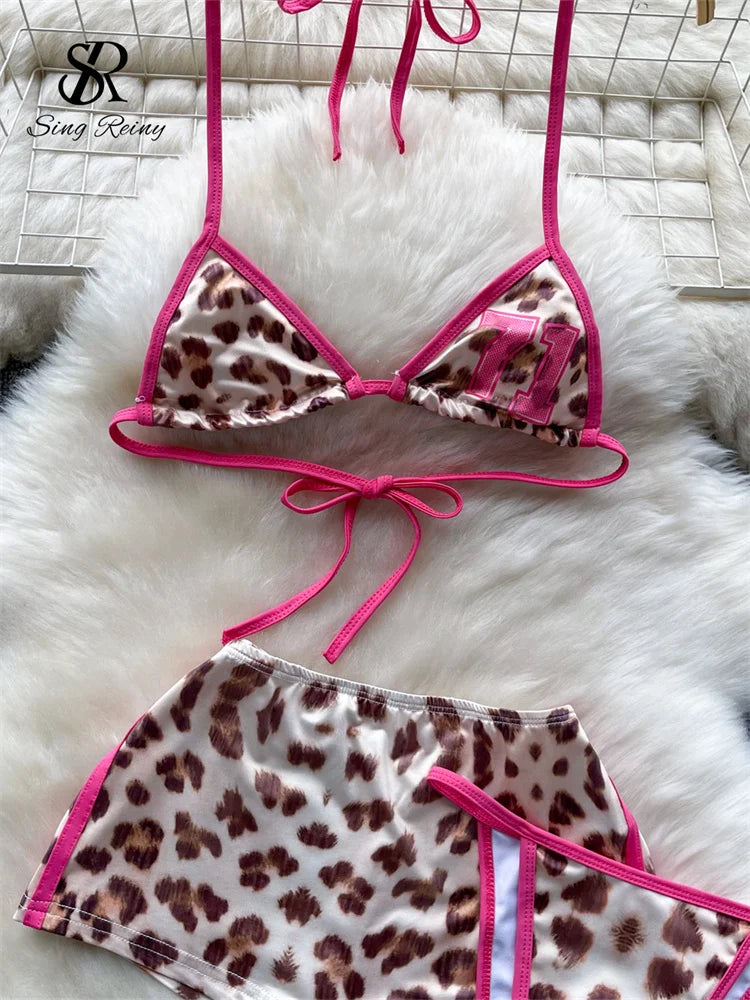 Leopard print bikini set with pink straps on a white fur surface, brand 'Sing Rely' visible.
