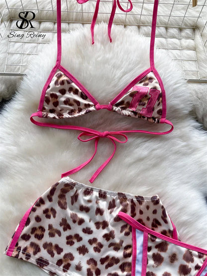 Leopard print bikini set with pink straps on a white fur surface, brand 'Sing Rely' visible.