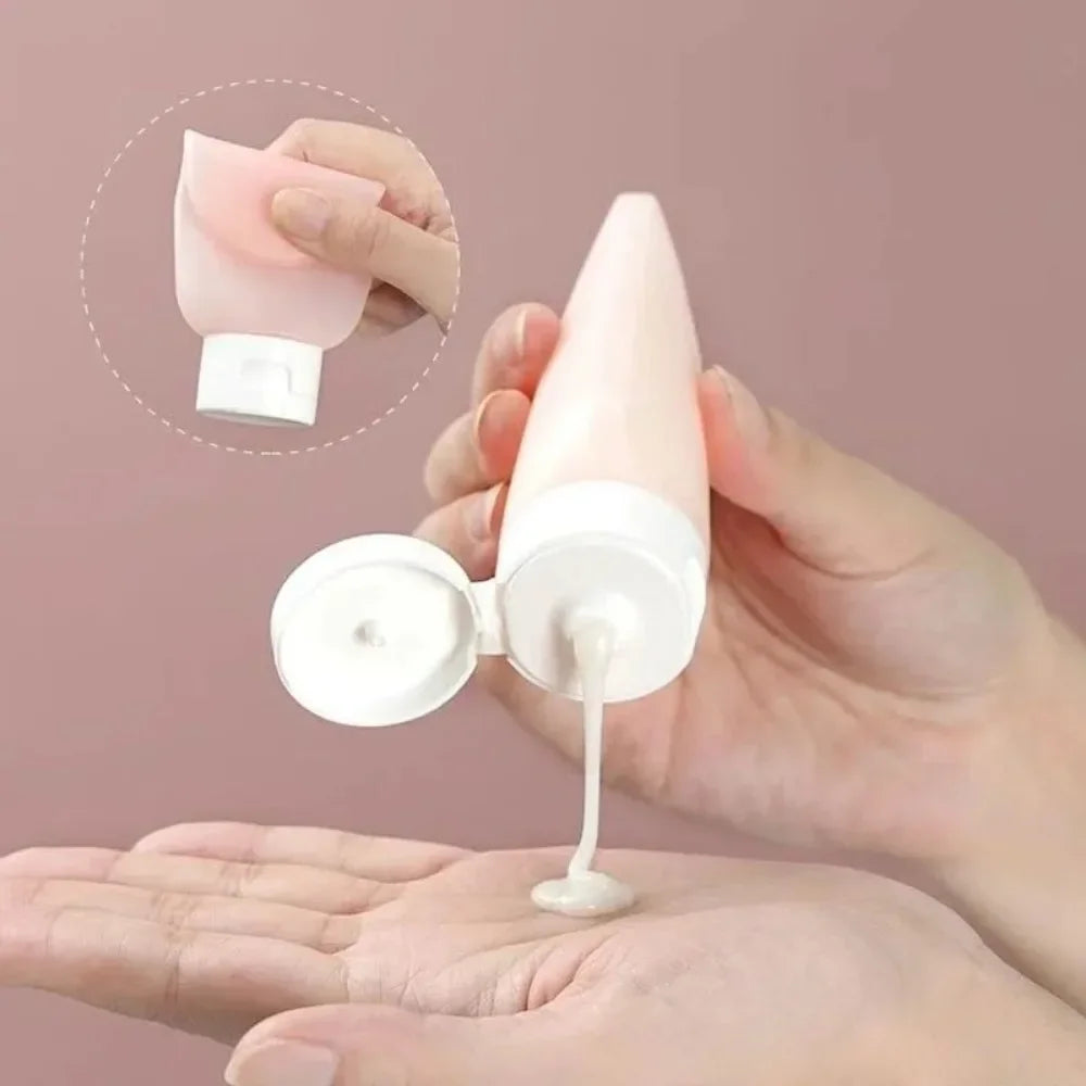 Hand holding a white cosmetic tube with pink cap, dispensing cream onto another hand against a pink background.