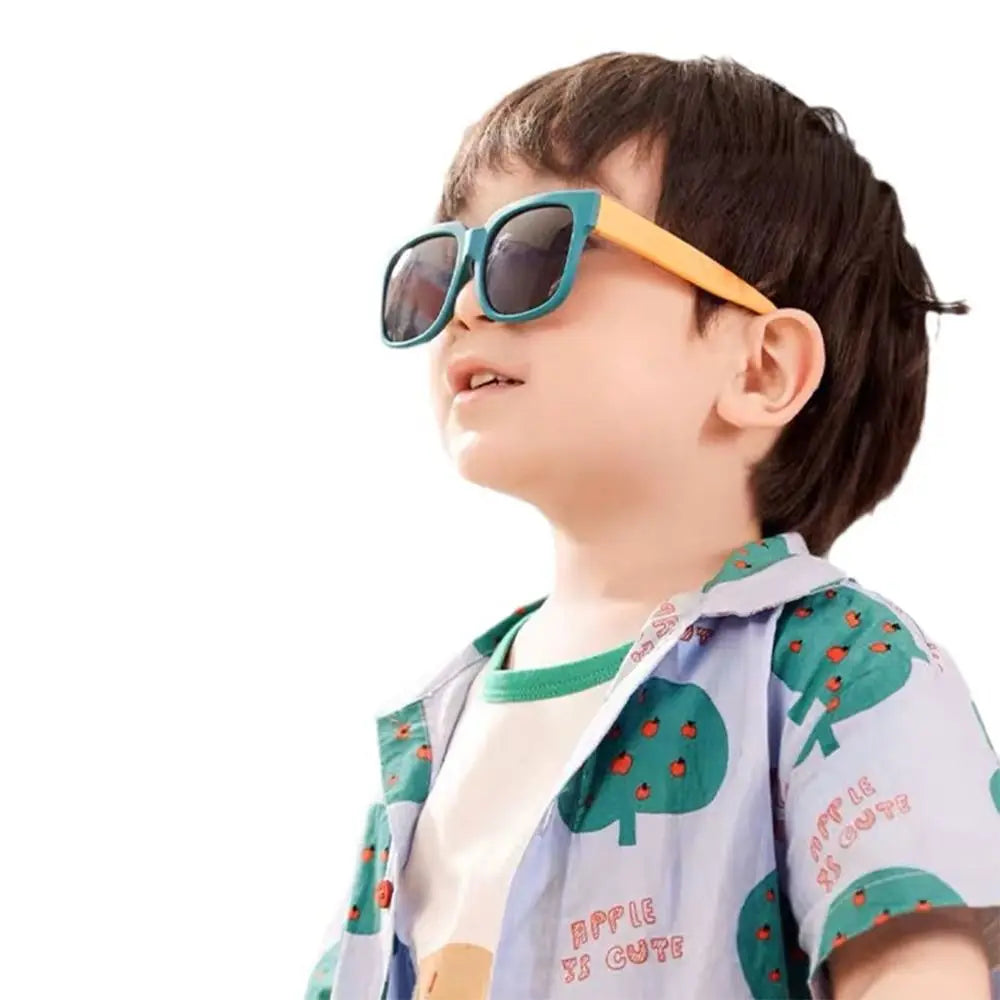 Child wearing colorful sunglasses and a patterned shirt on a white background