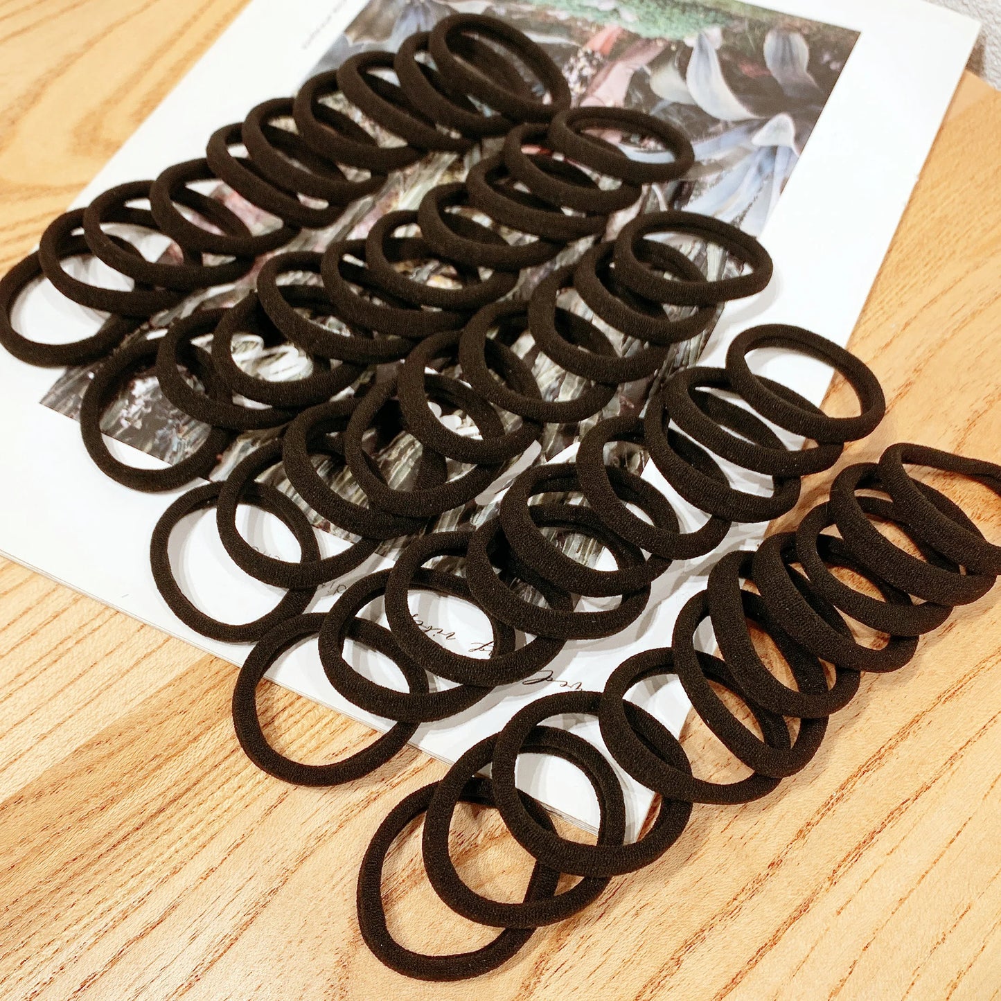 Multiple black hair ties on a wooden surface