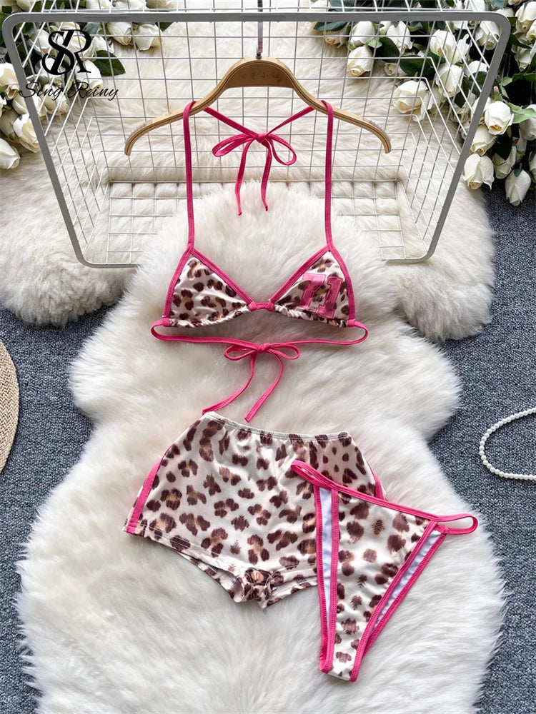 Leopard print bikini set with pink straps on a hanger against a textured white background.
