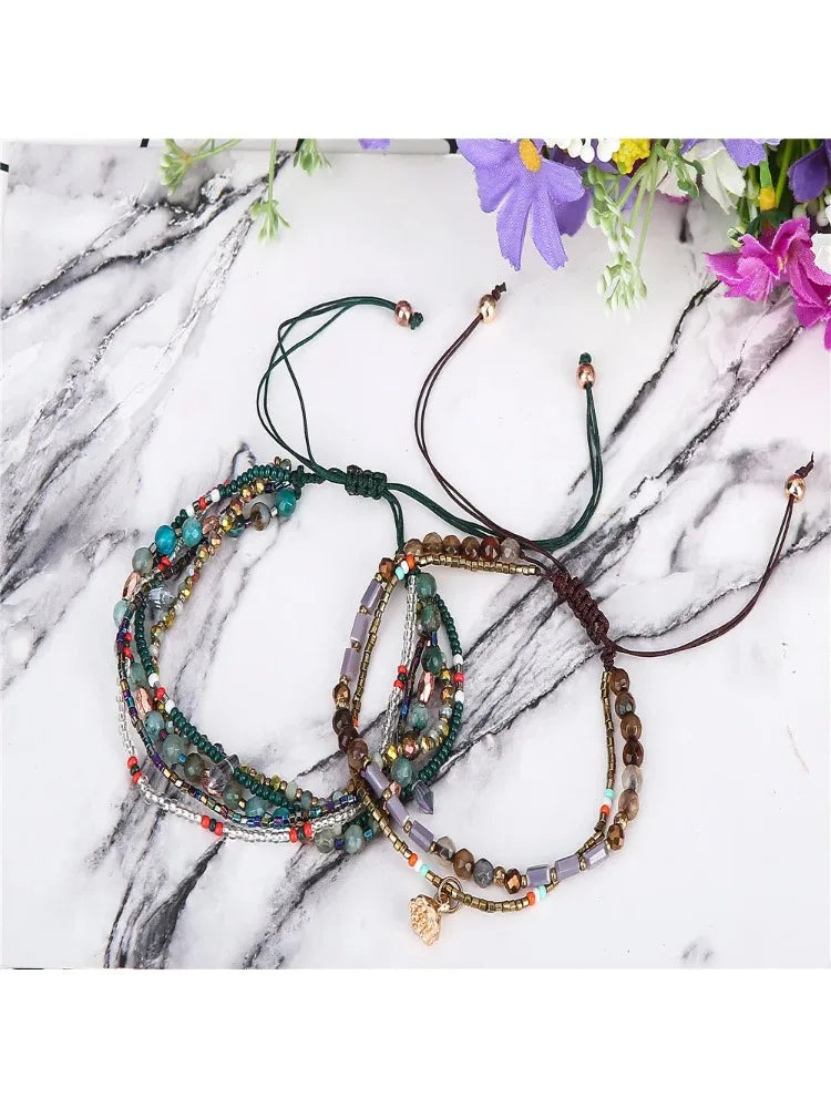 Three beaded bracelets on a marble surface with flowers in the background