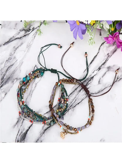 Three beaded bracelets on a marble surface with flowers in the background