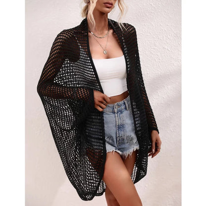 Woman wearing a black mesh cover-up over a white top and denim shorts on a light background