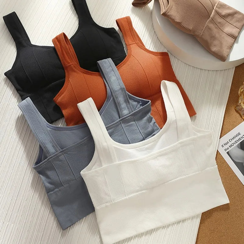Set of four women's tank tops in black, brown, gray, and white on a textured surface.