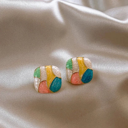 Colorful geometric earrings on a beige fabric background