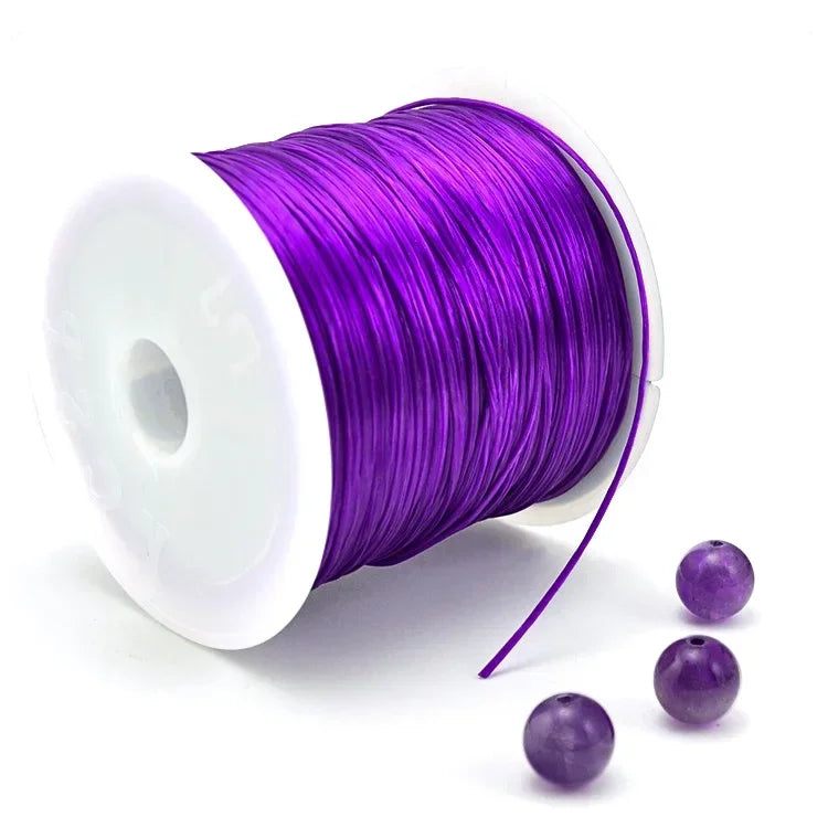 Spool of purple thread with three beads on a white background