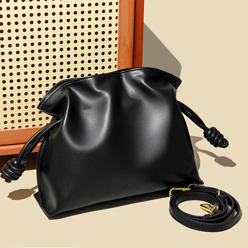 Black leather handbag with a strap on a beige background