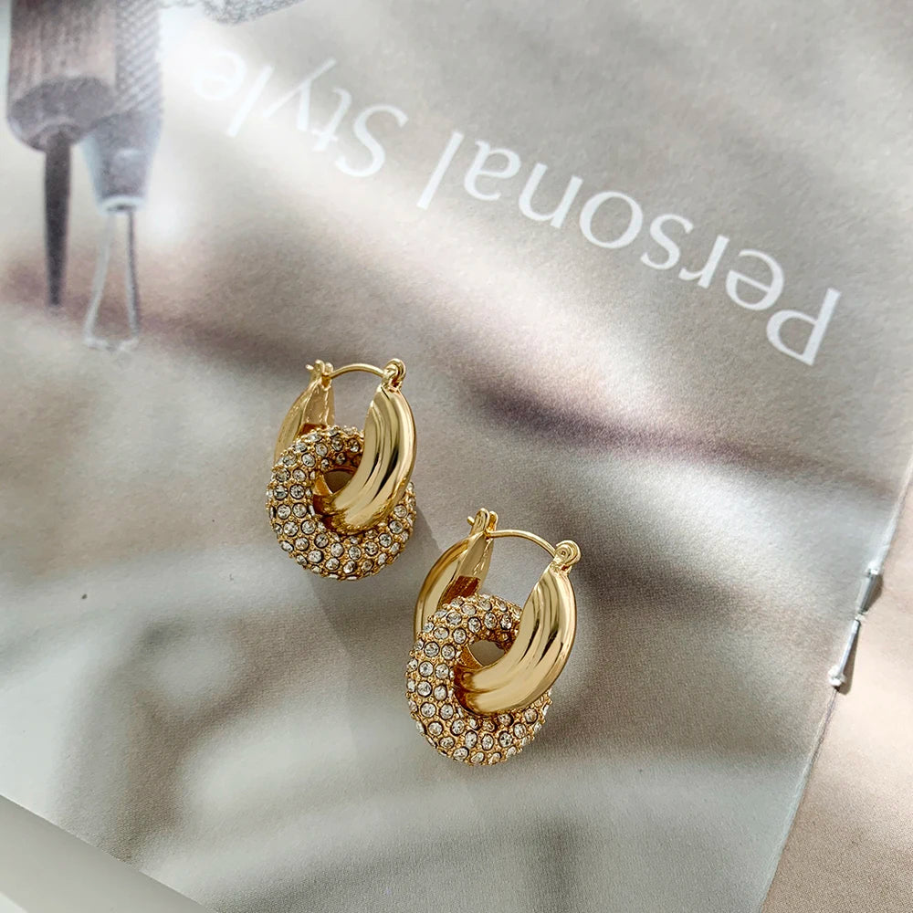 Gold hoop earrings with embedded stones on a light background