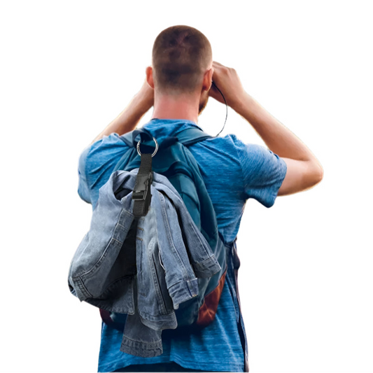 Person with a backpack looking through binoculars in a scenic outdoor setting
