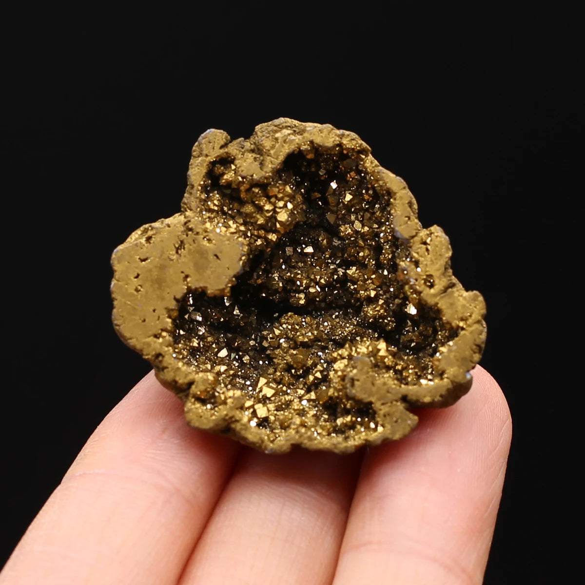 Gold geode held in a hand against a black background
