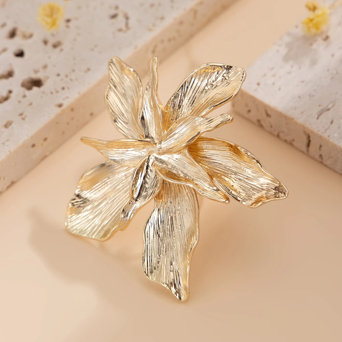 Gold floral brooch on a beige background