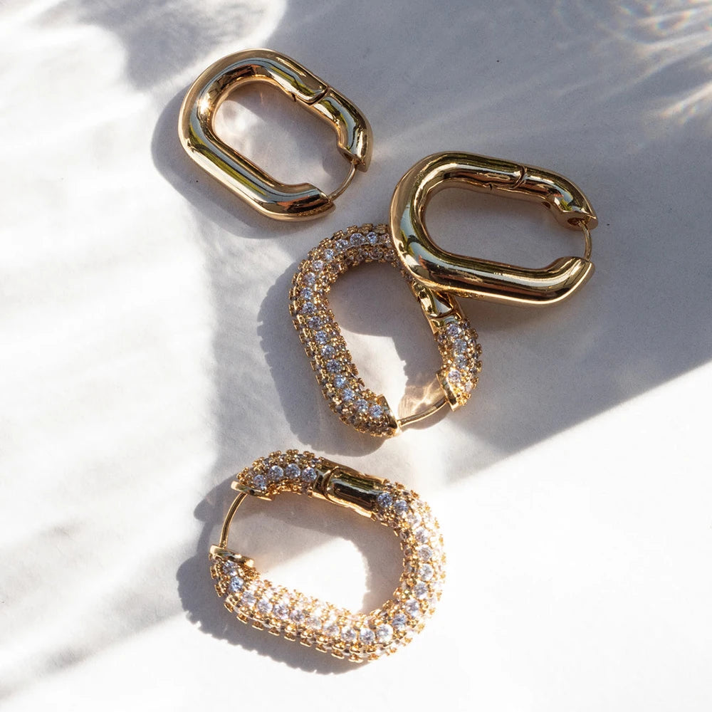 Gold hoop earrings with embedded stones on a light background