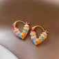 Colorful hoop earrings on a brown fabric background