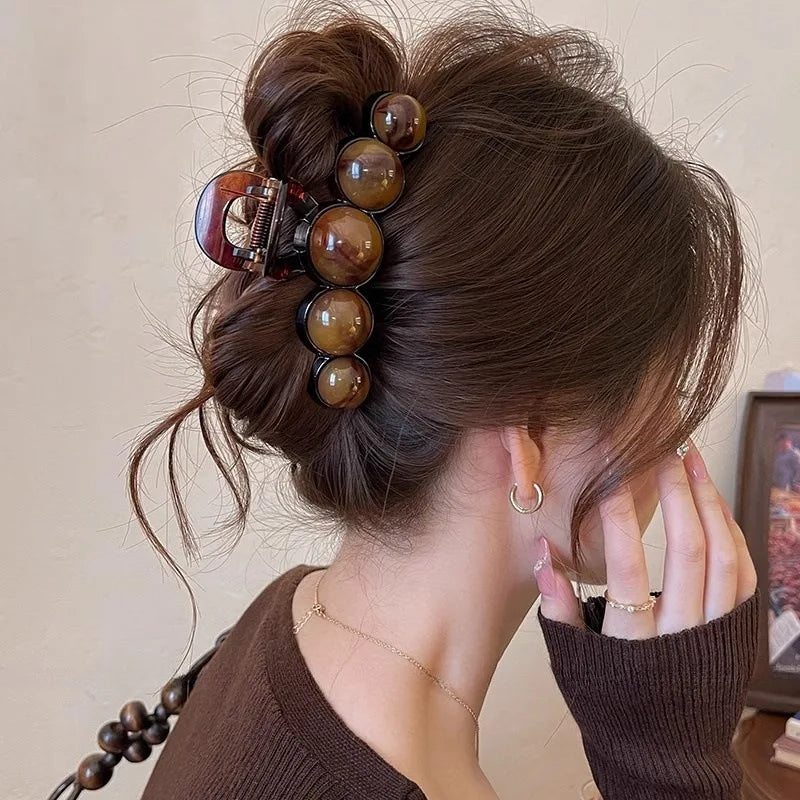 Person with hair styled in an updo using brown hair accessories against a neutral background