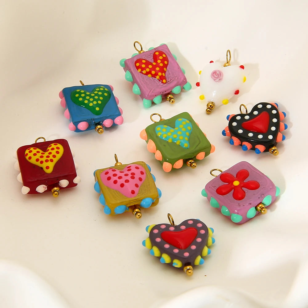 Colorful polymer clay charms with heart and flower designs on a white background
