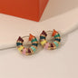 Colorful hoop earrings with gold accents on a beige surface.