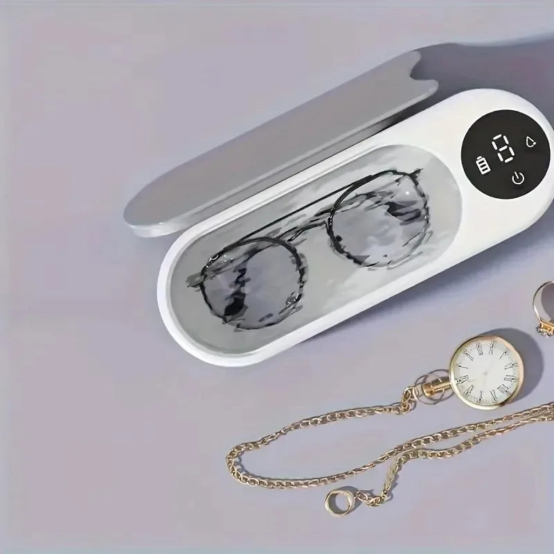 White electronic device with a digital display and compartments for sunglasses and a watch on a light gray background.