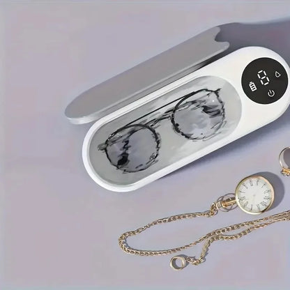 White electronic device with a digital display and compartments for sunglasses and a watch on a light gray background.