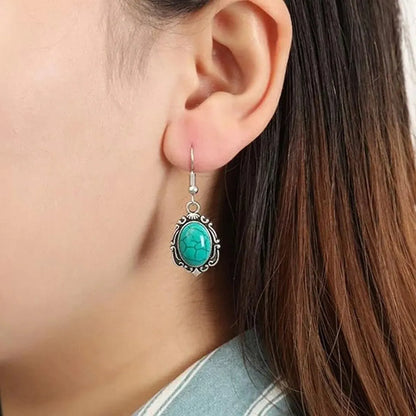 Turquoise earring worn by a person with brown hair.