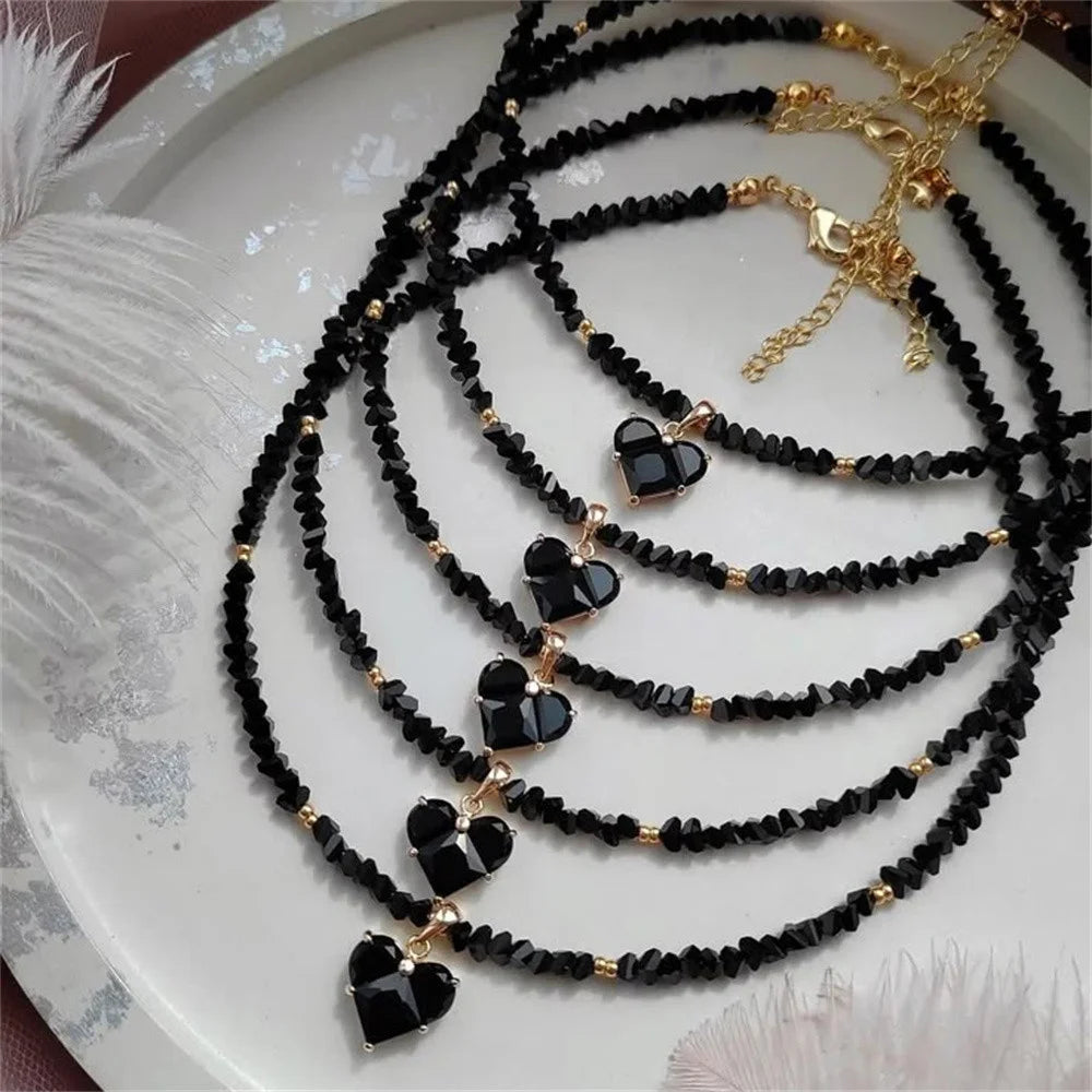 Black beaded necklaces with heart-shaped charms on a white plate.