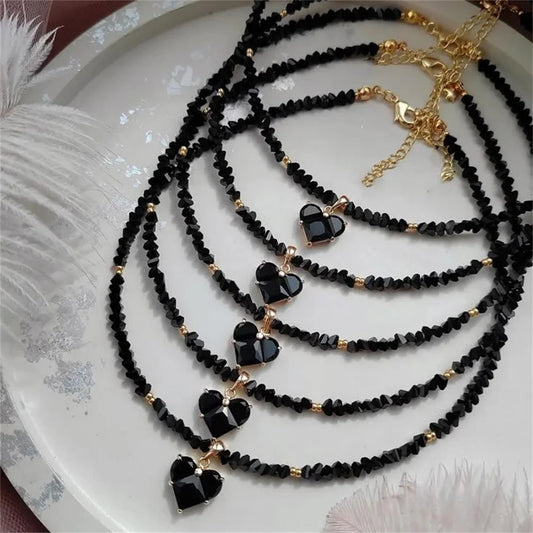 Black beaded necklaces with heart-shaped charms on a white plate.