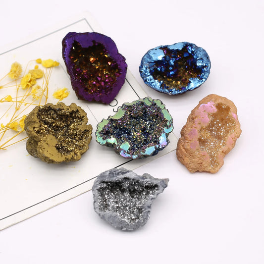 Collection of colorful geode crystals on a white surface with yellow flowers.
