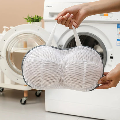 Person holding a mesh laundry bag in front of a washing machine