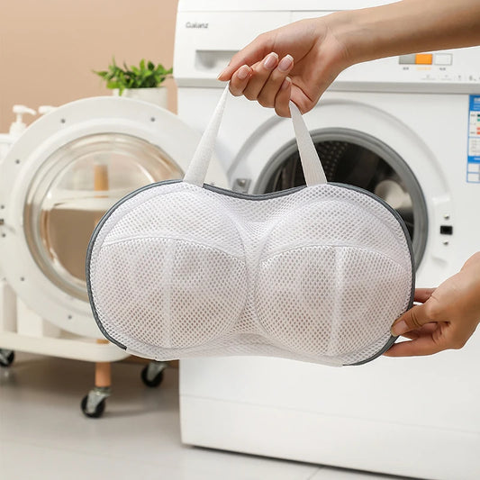 Person holding a mesh laundry bag in front of a washing machine