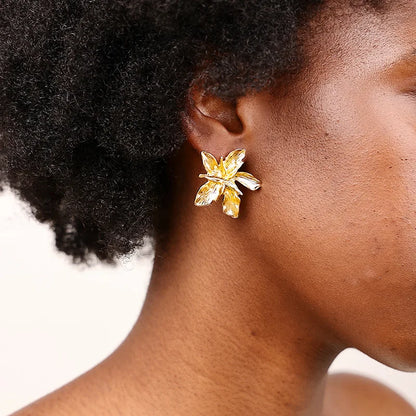 Gold butterfly earrings worn by a person with a neutral background