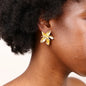 Gold butterfly earrings worn by a person with a neutral background