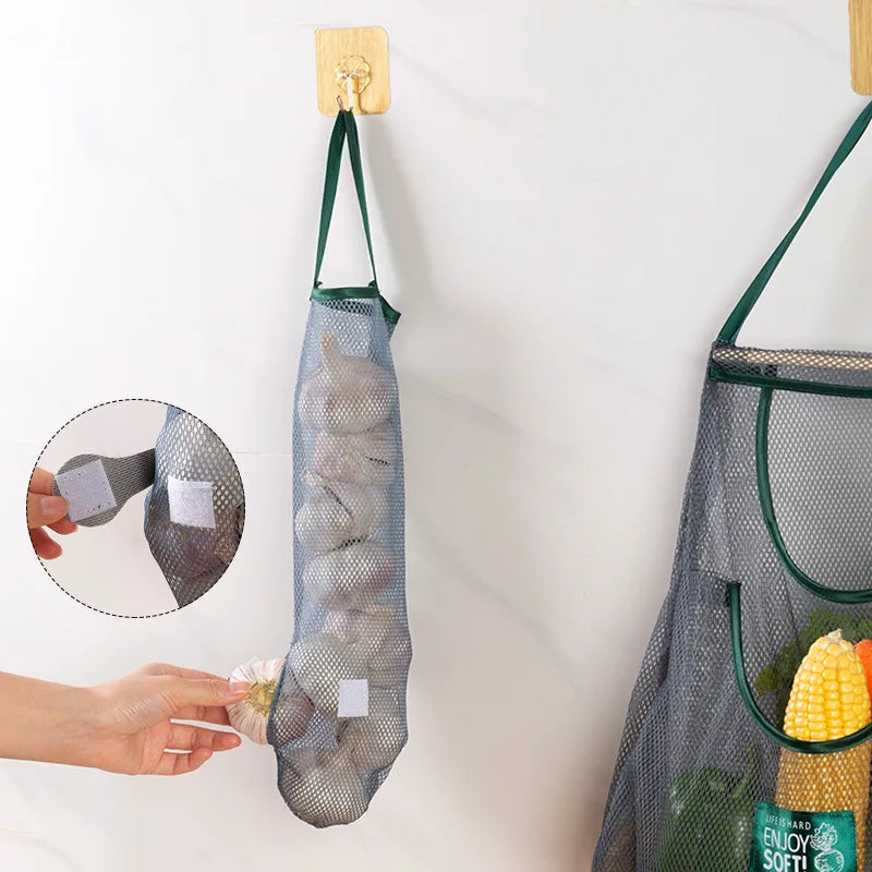 Mesh grocery bag with handles, filled with vegetables, hanging on a hook.