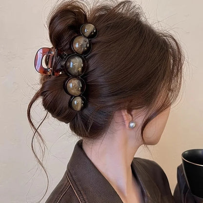 Person with hair styled in an updo using hair clips, wearing a brown garment.