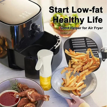 Air fryer with french fries, dipping sauce, and a bottle of oil on a table.